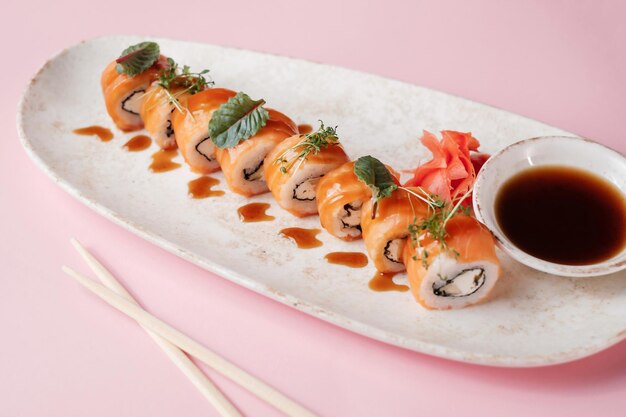 Sushi roll set with chopsticks on pink background side view