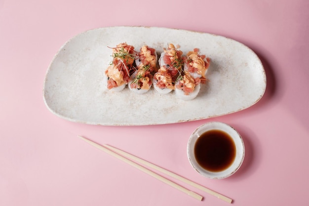 Sushi roll set with chopsticks on pink background top view