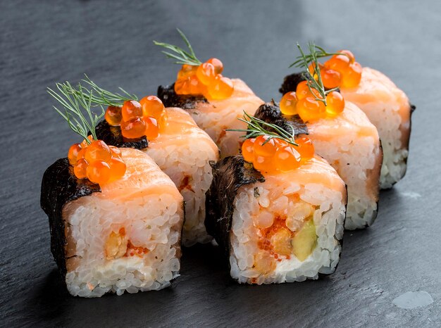 Sushi roll with salmon and caviar on black background