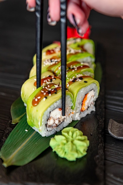 Sushi roll with smoked eel unagi covered by avocado and sesame seeds