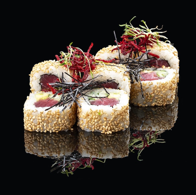 Sushi roll with tuna in sesame on glossy black background