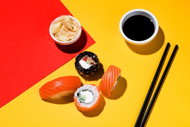 Sushi and rolls on a colored background, soy sauce, ginger. With a hard light