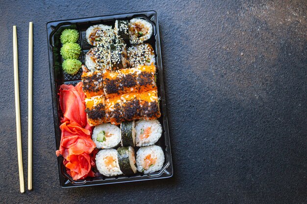 sushi rolls fish salmon, vegetables, ginger wasabi rice and nori on the table