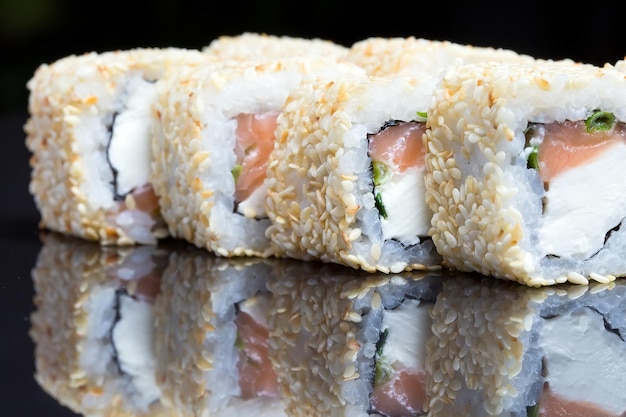 Sushi rolls shake chizu with sesame on a black background.