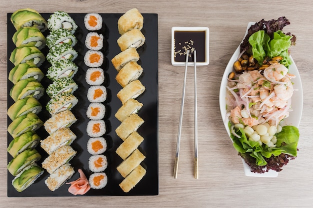 Sushi rolls with ceviche and soy sauce on a wooden table