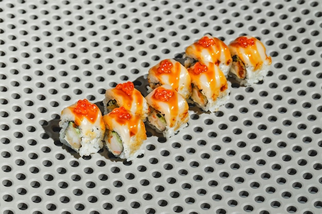 Sushi rolls with eel shrimp cucumber and cream cheese decorated with red caviar Hard light deep shadow