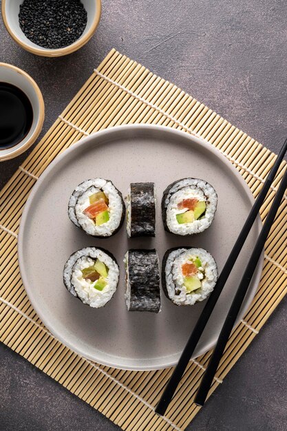 Sushi on round plate with chopsticks soy sauce ginger Homemade rolls with salmon avocado and cucumber