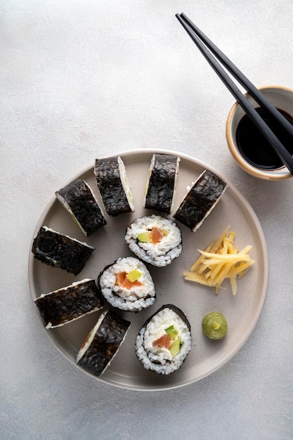 Sushi on round plate with chopsticks soy sauce ginger Homemade rolls with salmon avocado and cucumber