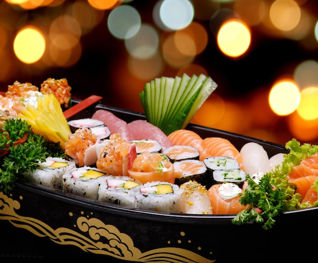 Sushi sashimi set in a wooden boat on a brown wooden table. With tune, prawn, shrimp, ginger