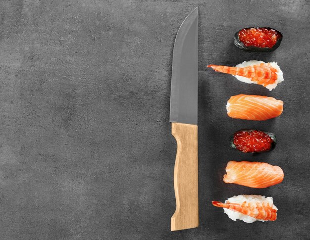 Sushi set and knife on dark background