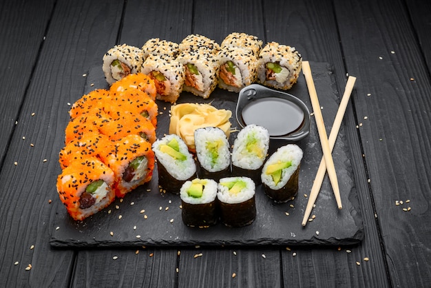 Sushi set nigiri and sushi rolls served on black stone slate