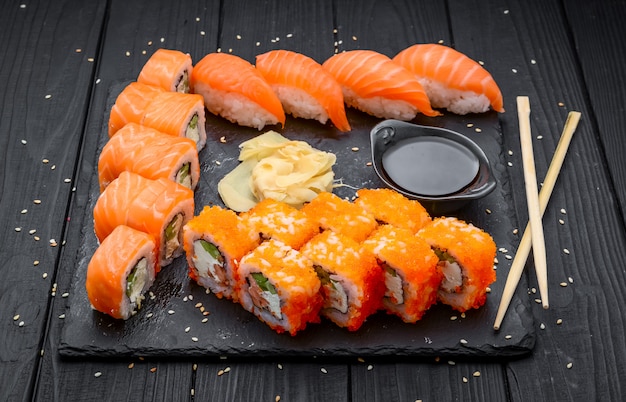 Sushi set nigiri and sushi rolls served on black stone slate