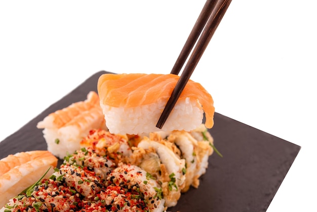 Sushi set with chopsticks and soy on a wooden plate ready to eat on grey background