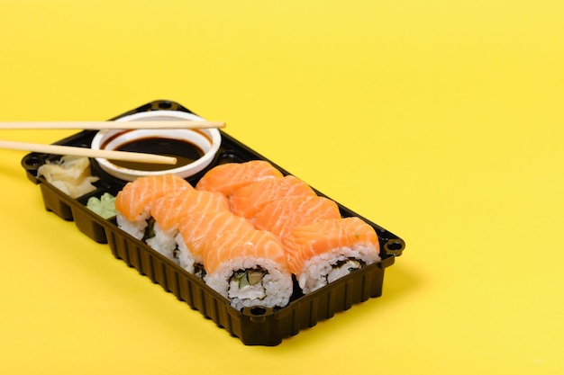 Sushi set with soy sauce and spices isolated on yellow background with copyspace