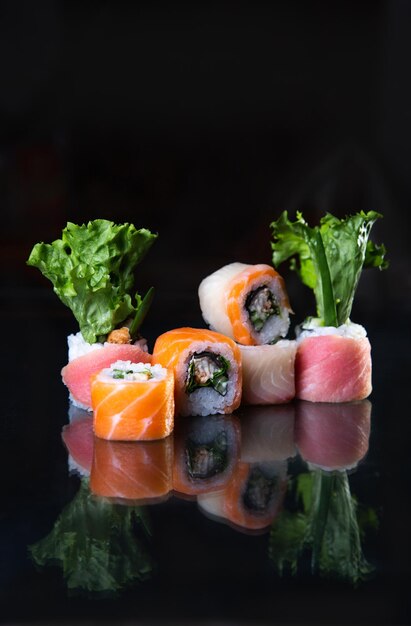 sushi with salad and reflection on a black background photos for menus