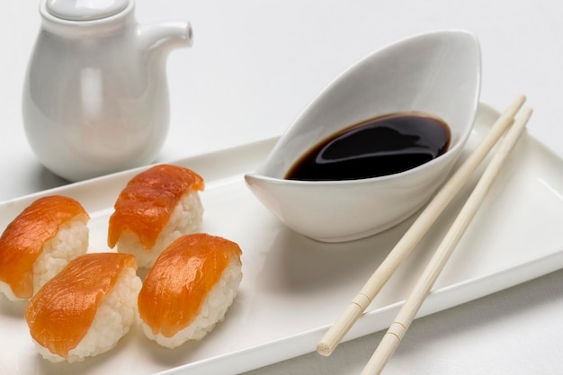 Sushi with salmon soy sauce in white bowl gravy boat and chopsticks