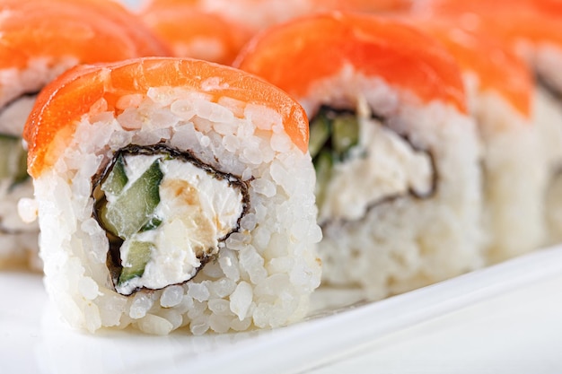 Sushi with salmon on a white plate with wasabi ginger soy chopsticks on a white background