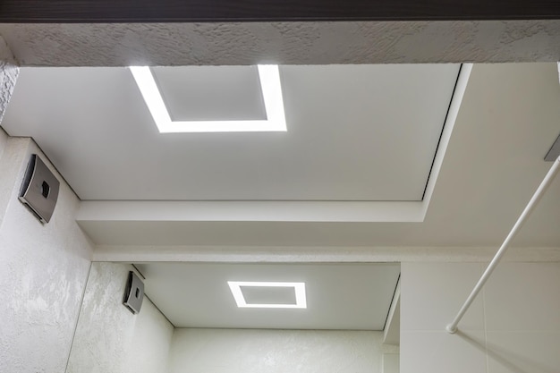 Suspended ceiling with halogen spots lamps and drywall construction in empty room in apartment or house Stretch ceiling white and complex shape