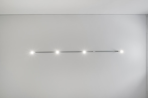 Suspended ceiling with halogen spots lamps and drywall construction in empty room in apartment or house Stretch ceiling white and complex shape