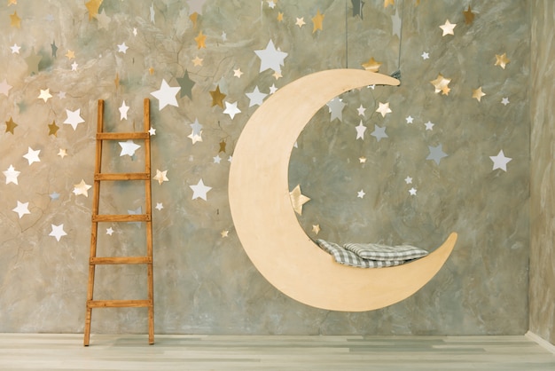 Suspended swing in the shape of the moon with stars.