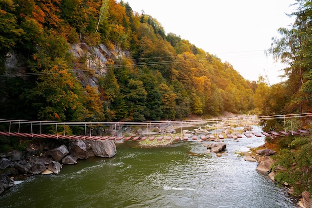 Suspension bridge on the Prut River in the city of Yaremche Waterfall Probiy Autumn landscape Carpathians Ukraine Selective soft focus