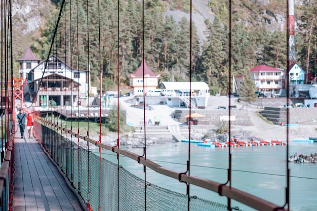 A suspension bridge over a wide river in the mountains. Safe crossing of the bridge from one bank to the other.