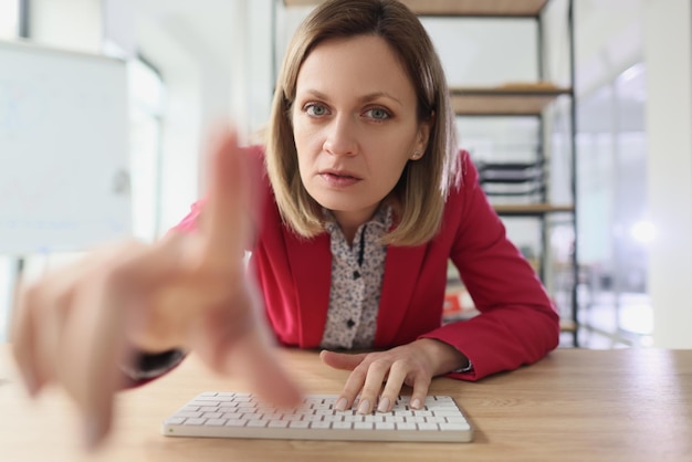 Suspicious woman points finger to monitor typing on keyboard