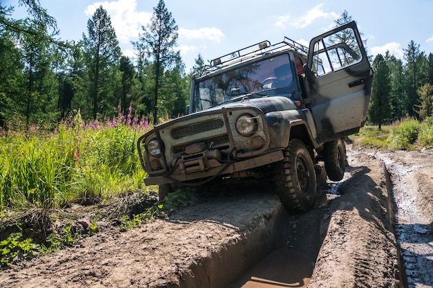 Photo suv stuck in a rut on a bad impassable road in the woods of siberia. russia