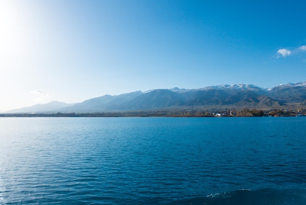 Sverny shore of Lake IssykKul Kyrgyzstan View from the ship to the shore Blue water of a mountain lake