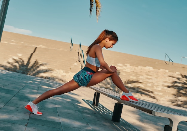 Sweat now and smile later. Beautiful young woman in sports clothing stretching while warming up outdoors