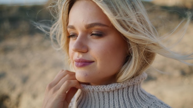 Sweater girl enjoying windy autumn portrait hair blowing in blond model face