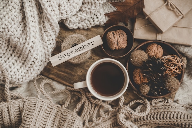 Sweaters and cup of tea with notebook, candle and knitting clothes