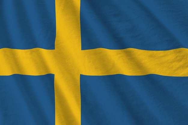 Sweden flag with big folds waving close up under the studio light indoors The official symbols and colors in banner