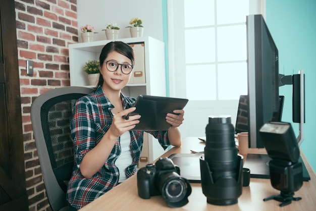 sweet attractive photo stock company female office worker holding mobile digital tablet computer checking photographer business picture and looking at camera smiling.