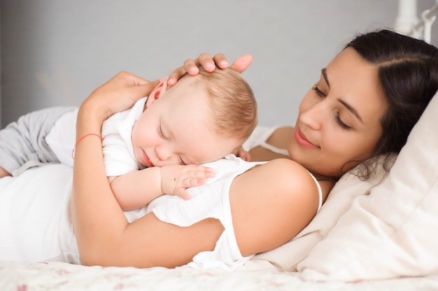 Sweet baby boy sleeping in bed with his mother