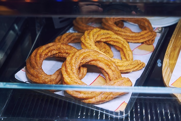 Sweet baked churros pretzel with cinnamon and caramel on counter in street cafe