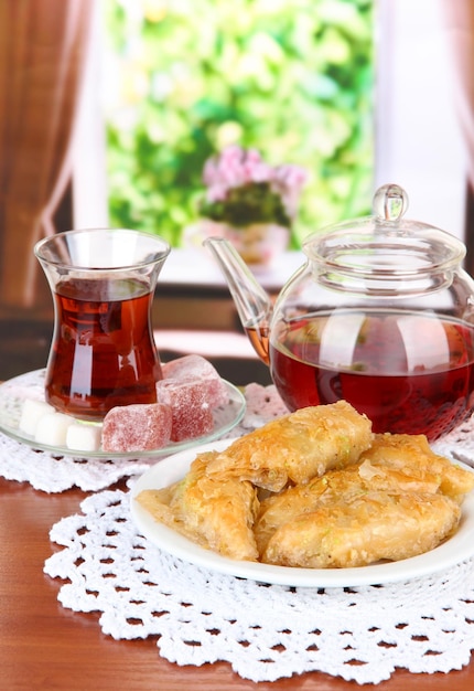 Sweet baklava on plate with tea on table in room