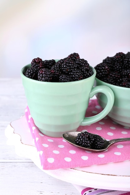 Sweet blackberries in color bowl on bright background