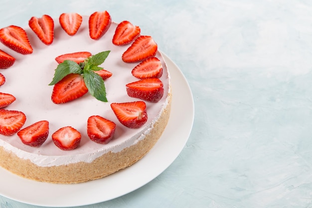 Sweet breakfast delicious cheesecake with fresh strawberries and mint homemade recipe without baking on a blue stone table Copy space