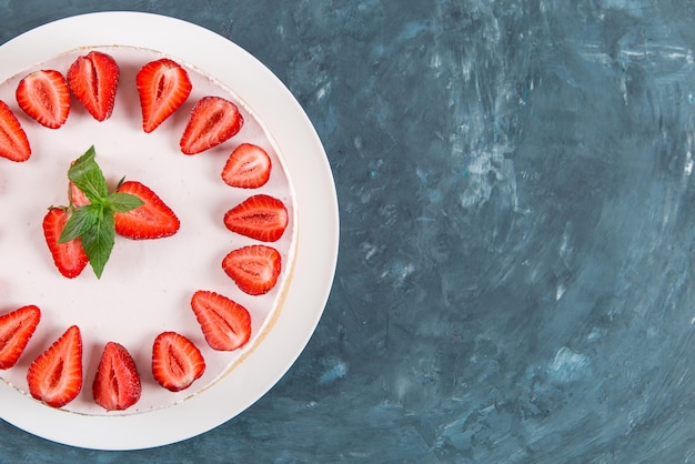 Sweet breakfast delicious cheesecake with fresh strawberries and mint homemade recipe without baking on a dark blue stone table Copy space