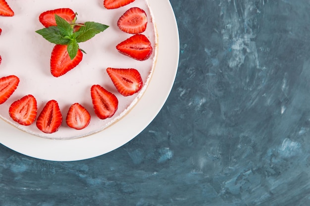 Sweet breakfast delicious cheesecake with fresh strawberries and mint homemade recipe without baking on a dark blue stone table Copy space