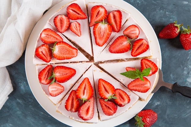 Sweet breakfast delicious cheesecake with fresh strawberries and mint homemade recipe without baking on a dark blue stone table Copy space