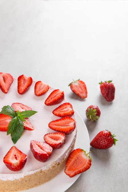 Sweet breakfast delicious cheesecake with fresh strawberries and mint homemade recipe without baking on a stone table Copy space