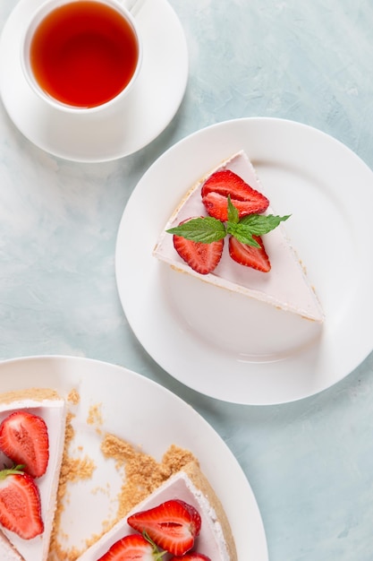 Sweet breakfast tea and delicious cheesecake with fresh strawberries and mint homemade recipe without baking on a blue stone table Copy space