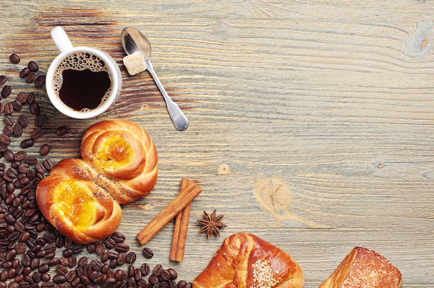 Sweet buns and coffee cup on old wooden table