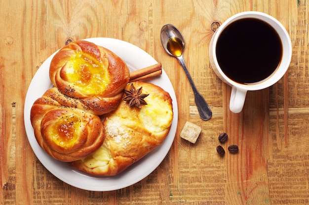 Sweet buns and coffee cup on old wooden table