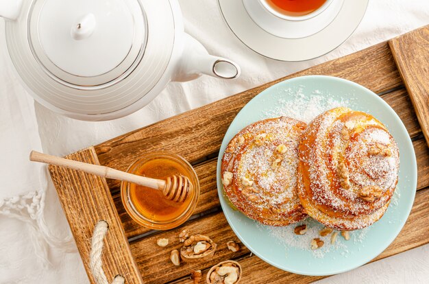 Photo sweet buns with walnuts, grated coconut and honey on a wooden tray