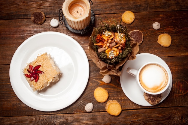 Sweet cake and cappuccino on festive wooden table