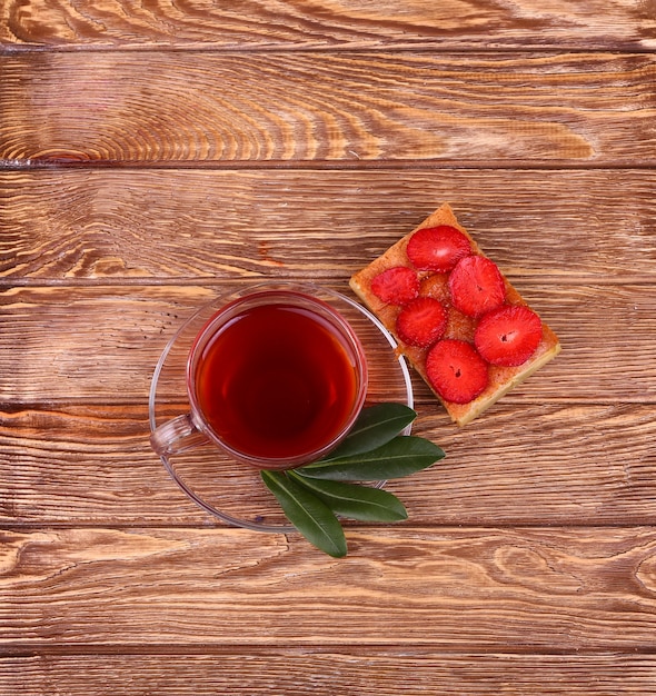 Sweet cake with cup of tea on wooden table