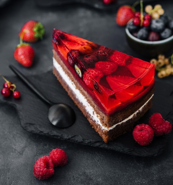 Sweet cake with fresh berries and jelly on old stone board